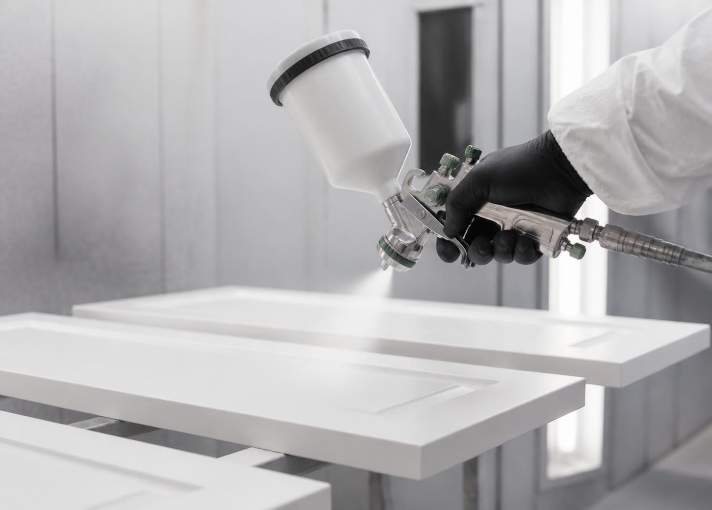 Spray gun applying a smooth white finish to cabinet doors